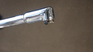 Krom metal mutfak musluğu iki damla su damlatıyor.