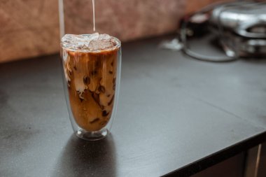 Yakın plan buzlu kahve. Masada süt var.