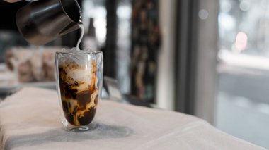 Yakın plan buzlu kahve. Masada süt var.