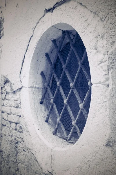 facade ancient building with round window and a iron lattice