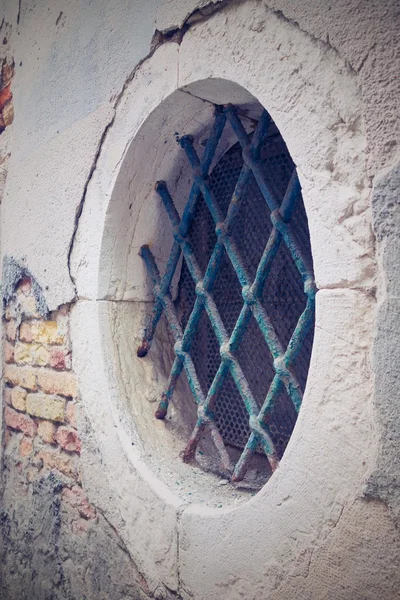 Facciata antico edificio con finestra rotonda e un reticolo di ferro — Foto Stock