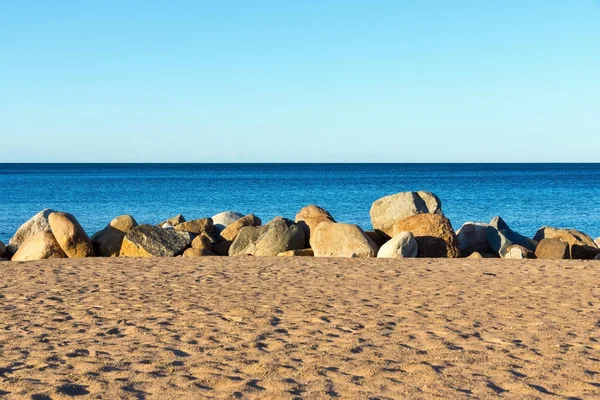 Praia de areia e grandes pedras em terra perto da água — Fotografia de Stock