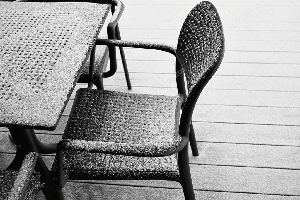 abstract snow-covered parts of the chair and table of black color and closeup outdoors with white snow