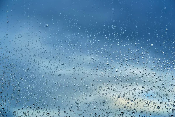 Abstrakte Wassertropfen Auf Dem Fensterglas Auf Einem Verschwommenen Blauen Bewölkten — Stockfoto