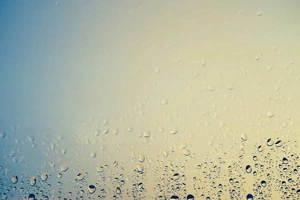 transparent glass window with raindrops against the background of an empty and clear sky