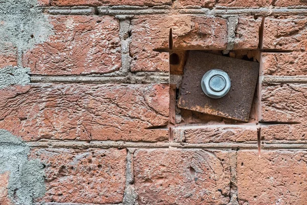 Placa de ferro e porca em uma parede de tijolo velho — Fotografia de Stock