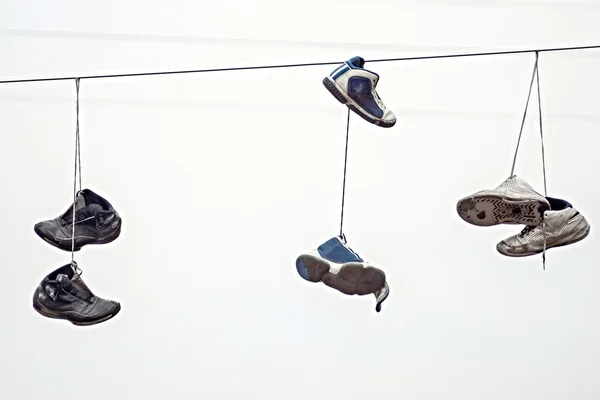 Tre coppie vecchie scarpe da ginnastica su fili — Foto Stock