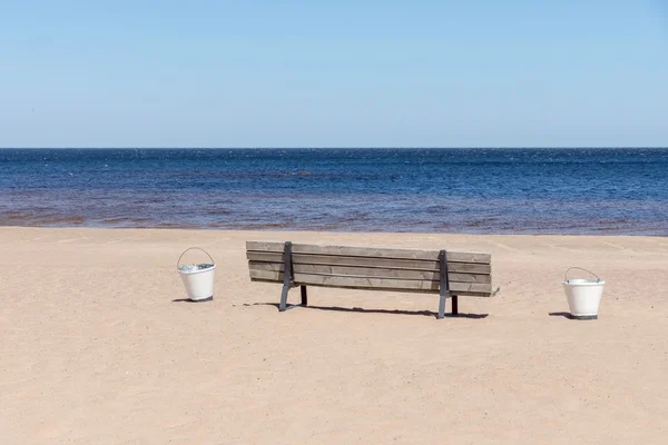 Banco de madeira na praia de areia litoral — Fotografia de Stock