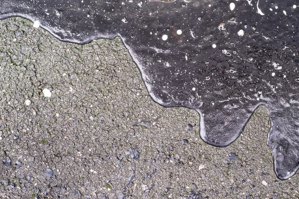 Абстрактная форма черного битума на асфальте с пятнами — стоковое фото
