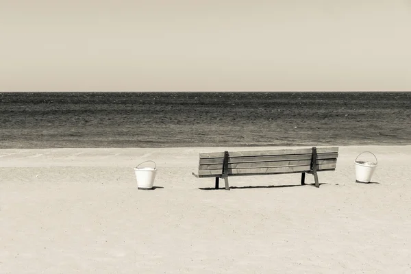 Panca in legno beige e secchi sulla spiaggia sabbiosa — Foto Stock