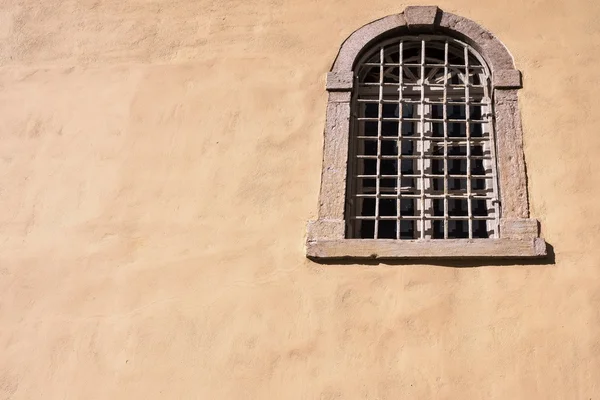 Vecchia finestra con un reticolo di ferro su una facciata di casa — Foto Stock