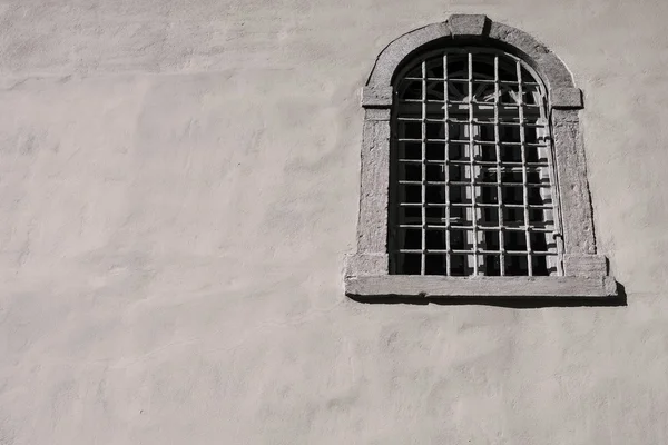 Vecchia finestra con un reticolo di ferro su una facciata di casa — Foto Stock