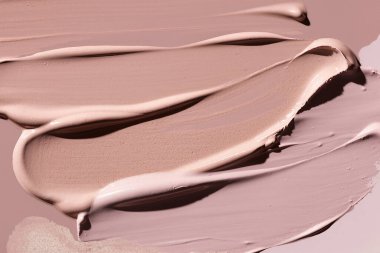 Yumuşak fırça darbeleri ve parlak kaplamalı kremalı, çıplak bej dokular. Güzellik ve makyaj için zarif kozmetik arka plan