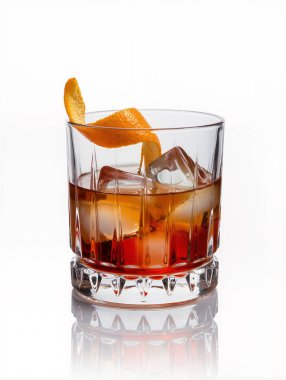 Kristal bardakta, beyaz arka planda izole edilmiş, buz küpleri ve portakal dilimli zarif Negroni kokteyli..