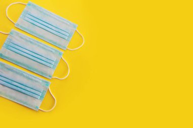 Sarı arka planda mavi tıbbi maskeler.