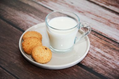 Bardakta beyaz süt ve kurabiye.