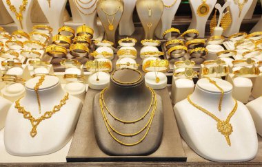 Güzel kadın mücevherleri altın kolyeler ve vitrininde dekoratif desenler olan bilezikler.