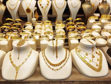 Güzel kadın mücevherleri altın kolyeler ve vitrininde dekoratif desenler olan bilezikler.