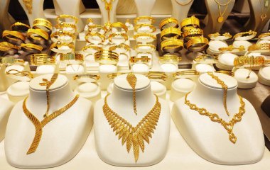 Güzel kadın mücevherleri altın kolyeler ve vitrininde dekoratif desenler olan bilezikler.