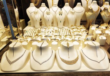 Güzel kadın mücevherleri altın kolyeler ve vitrininde dekoratif desenler olan bilezikler.