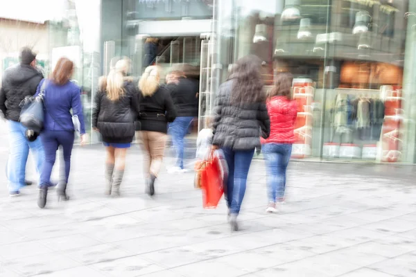 A shopper walking in front of shop window at dusk — Stock Photo, Image