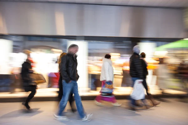 Shopper promenader framför skyltfönster i skymningen — Stockfoto