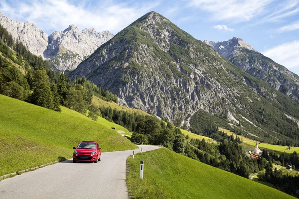 Gramais, Austria, 12 de septiembre de 2015: Red car driving on alpine road, Gramais, Austrian — Foto de Stock