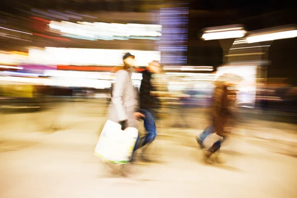 Young women walking past display windows at dusk — Stock Photo, Image