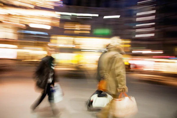 Människor gå ner shoppinggatan i skymningen — Stockfoto