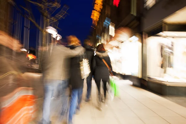 Толпа покупателей идет по тротуару в сумерках — стоковое фото