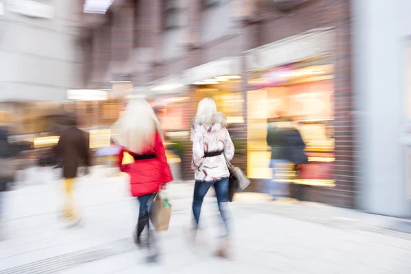 A young shoppers walking against shop window — Stock Photo, Image