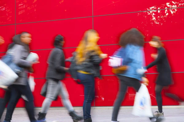 Shopper chůzi proti červené zdi — Stock fotografie
