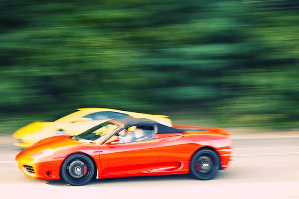 Červené a žluté auto rychle na venkovské silnici — Stock fotografie