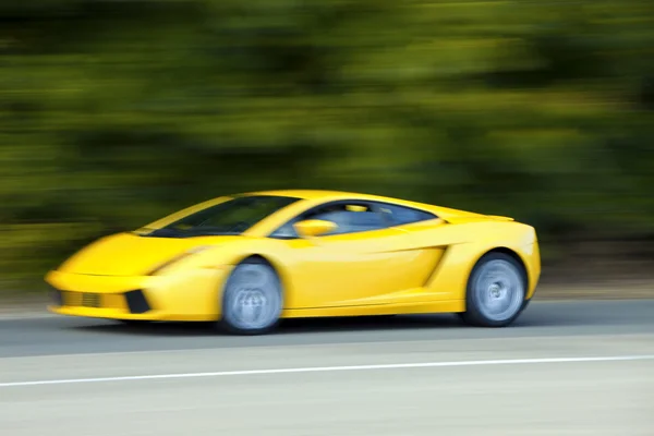 Yellow car driving fast on country road — Stock Photo, Image