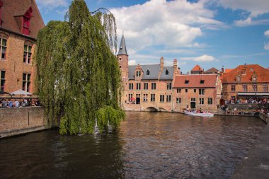 Bruges, Belçika - 12 Mayıs 2018: Turistler ve yerel halk, güneşli bir günde Su Kanalı 'nın yanında yürür