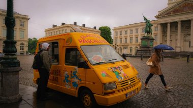 Brüksel, Belçika - 13 Mayıs 2018: Belçika sokak yemekleriyle dolu bir karavanın yanında taze kızarmış Belçika Waffle 'ını bekleyen genç bir adam.