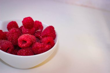 Birkaç olgun ahududu tabakta. Fotokopi alanı olan beyaz bir zemin.