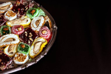 Doğulu tatlılar yuvarlak bir metal tepside koyu bir arka planda