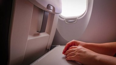 Eller, iskemlenin katlanan masasında, lombozun yanındaki uçağın kabininde.