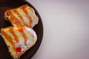 İki parça balkabaklı cheesecake, beyaz arka planda kil bir tabakta duruyor.