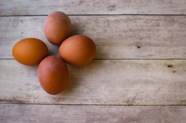 Tahta arka planda dört kırmızı tavuk yumurtası.