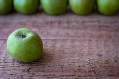 Yeşil elmalar ahşap bir yüzeyde durur.