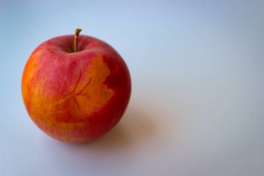 Beyaz bir yüzeyde kırmızı elma duruyor.