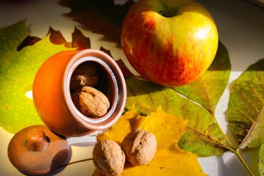 Sonbahar hala hayattır. Yapraklar, fındıklar, elmalar ve kil sürahi