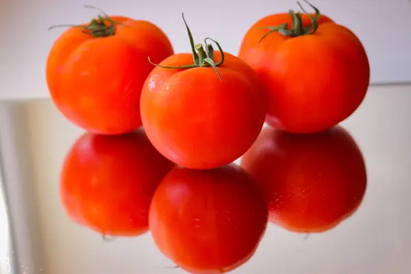 Varios Tomates Rojos Una Superficie Espejo — Foto de Stock