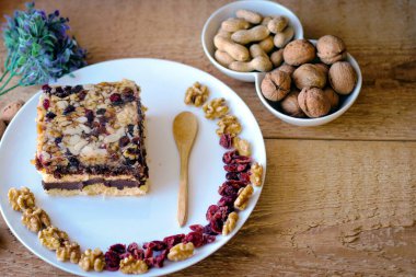 Beyaz tabakta bir parça çikolatalı fındıklı kek. Ceviz ve tahta kaşık yakınlarda duruyor.