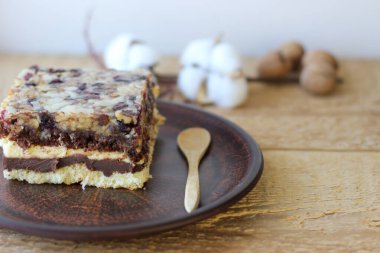 Kil tabakta bir parça çikolatalı cevizli kek. Yanında ceviz ve pamuk dalı var.