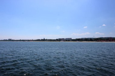 Sopot plajının panoramik manzarası ve kırmızı çatıları, tarihi binaları ve Baltık Denizi 'nden görünen ormanlık tepeleri berrak mavi gökyüzü altında..