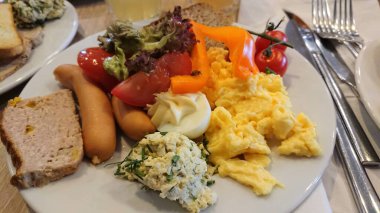 Otelin kahvaltı tabağıyla çırpılmış yumurta sosis sebze ekmek ve peynir sabah yemeğinde servis edilir..