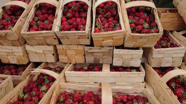 Yerel pazarda ahşap sepetlerde sergilenen taze olgun çileklerin üst görüntüsü. Doğal mevsimlik meyve hasadı kavramı.